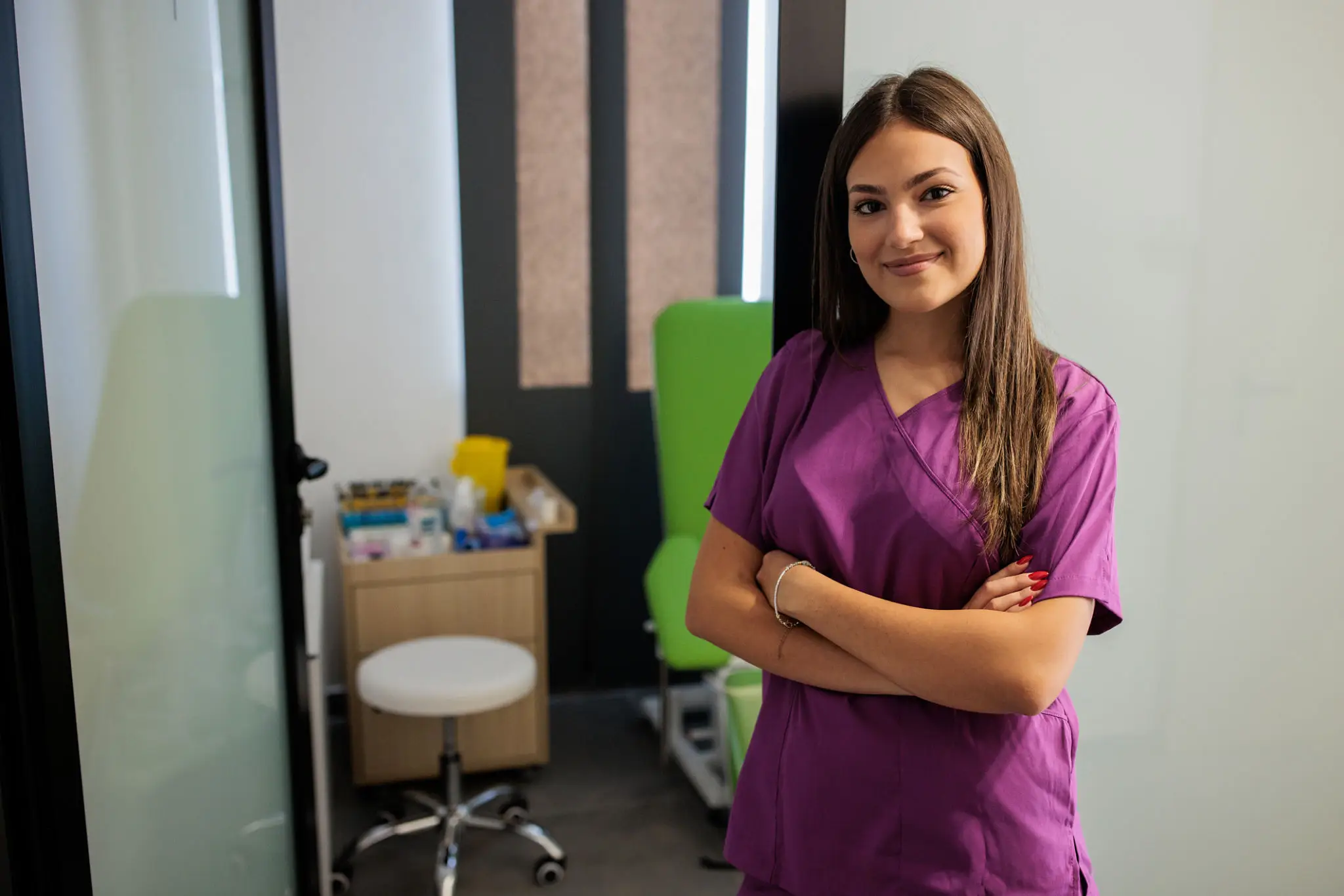 Smiling woman in purple uniform, clinic background.