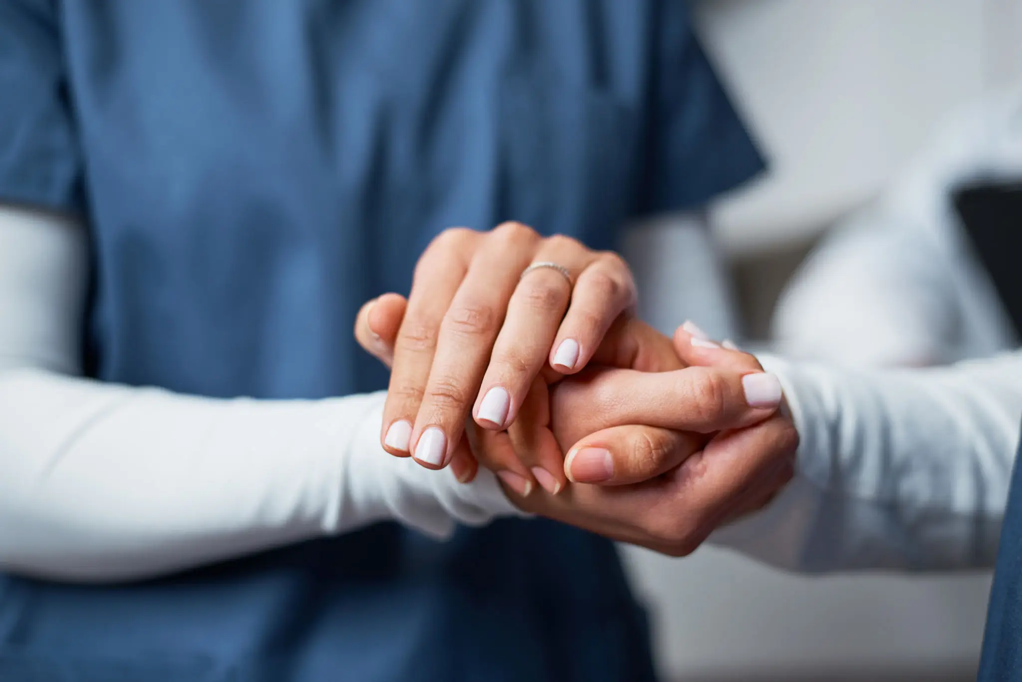 Healthcare worker comforting patient's hand gently.