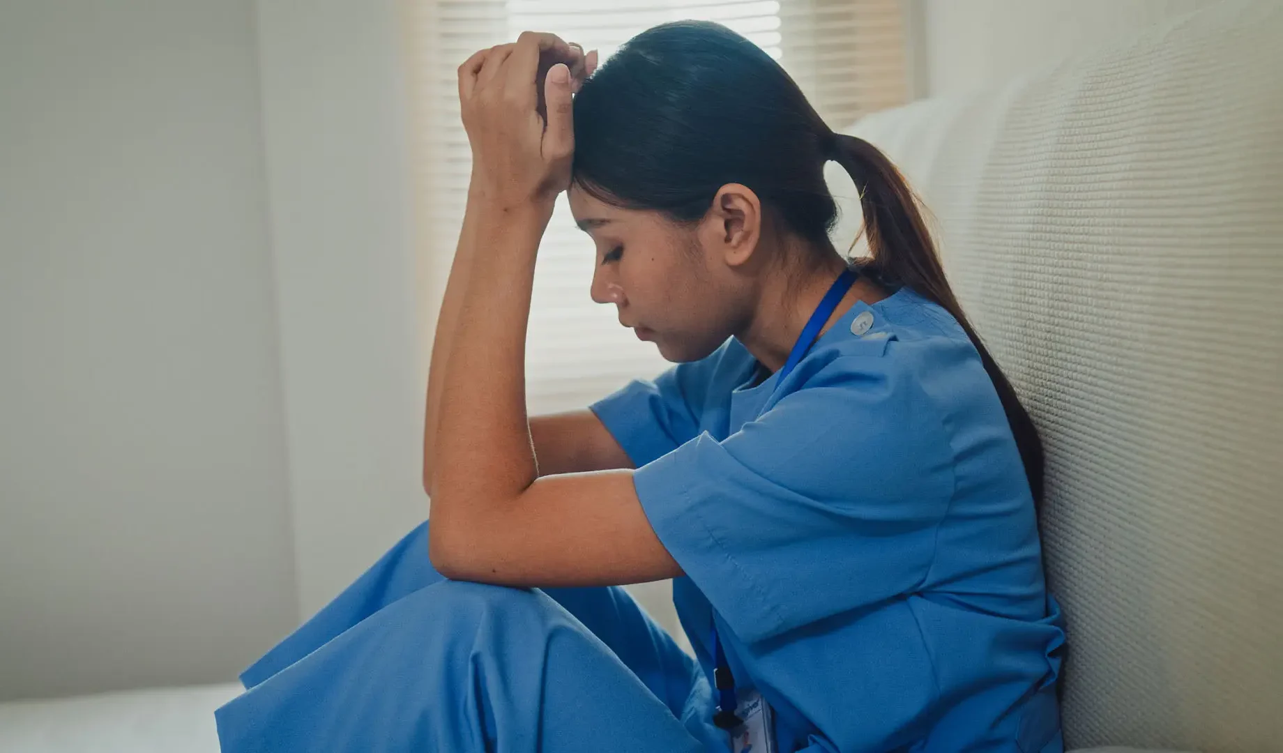 Nurse sitting with head in hands.