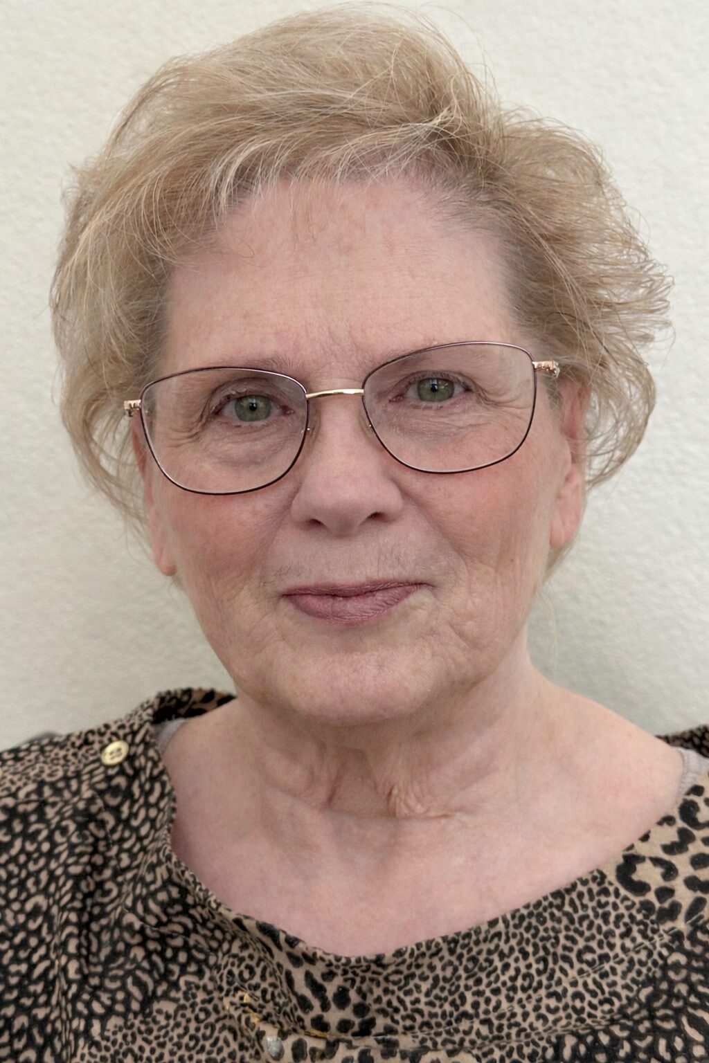 Elderly woman with glasses and leopard print.