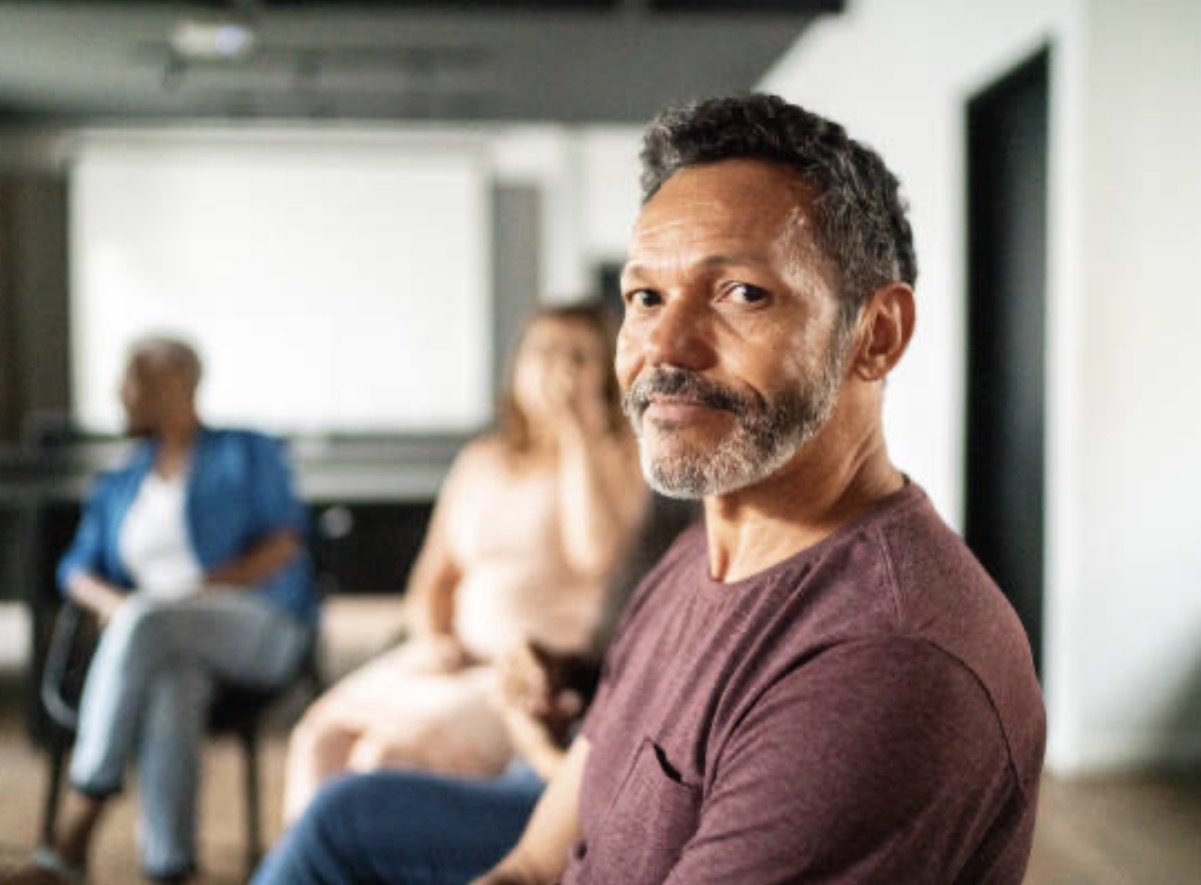 Man sitting with others in a room.