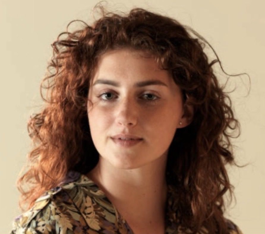 Curly-haired woman in a floral blouse.