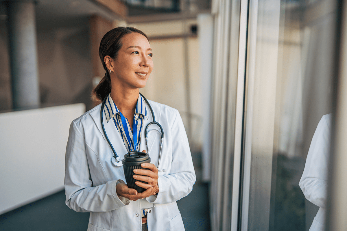 Doctor smiling and holding a coffee cup.
