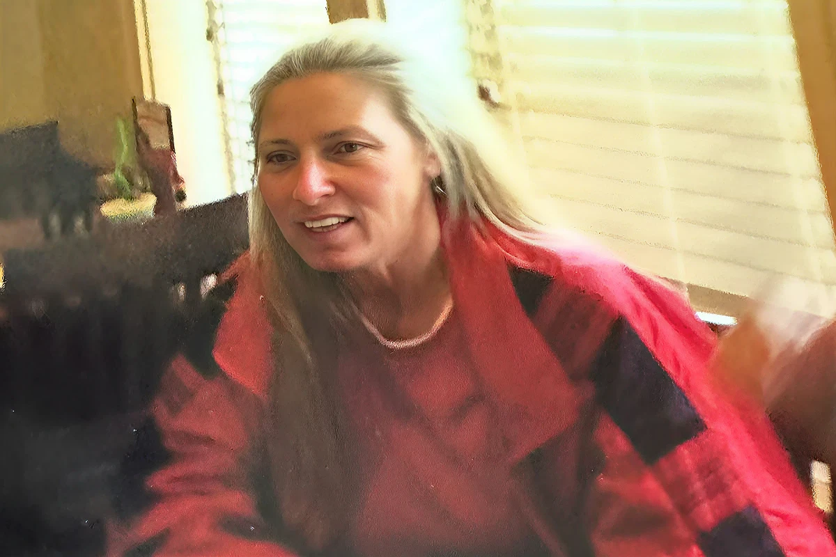 Woman in red plaid shirt indoors, smiling.