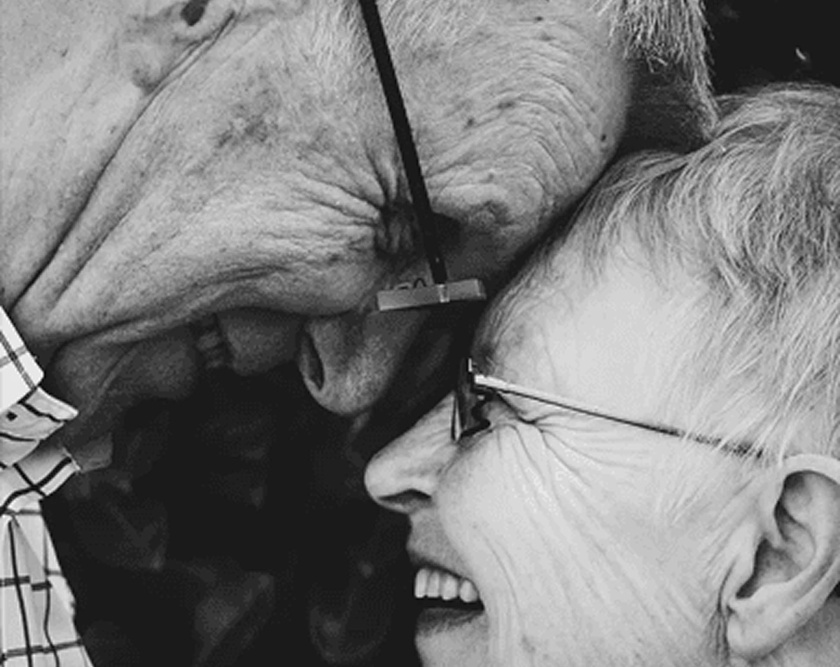 Elderly couple smiling, heads touching affectionately.