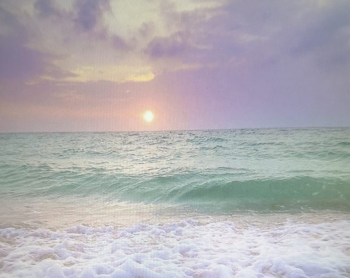 Sunset over ocean with gentle waves.